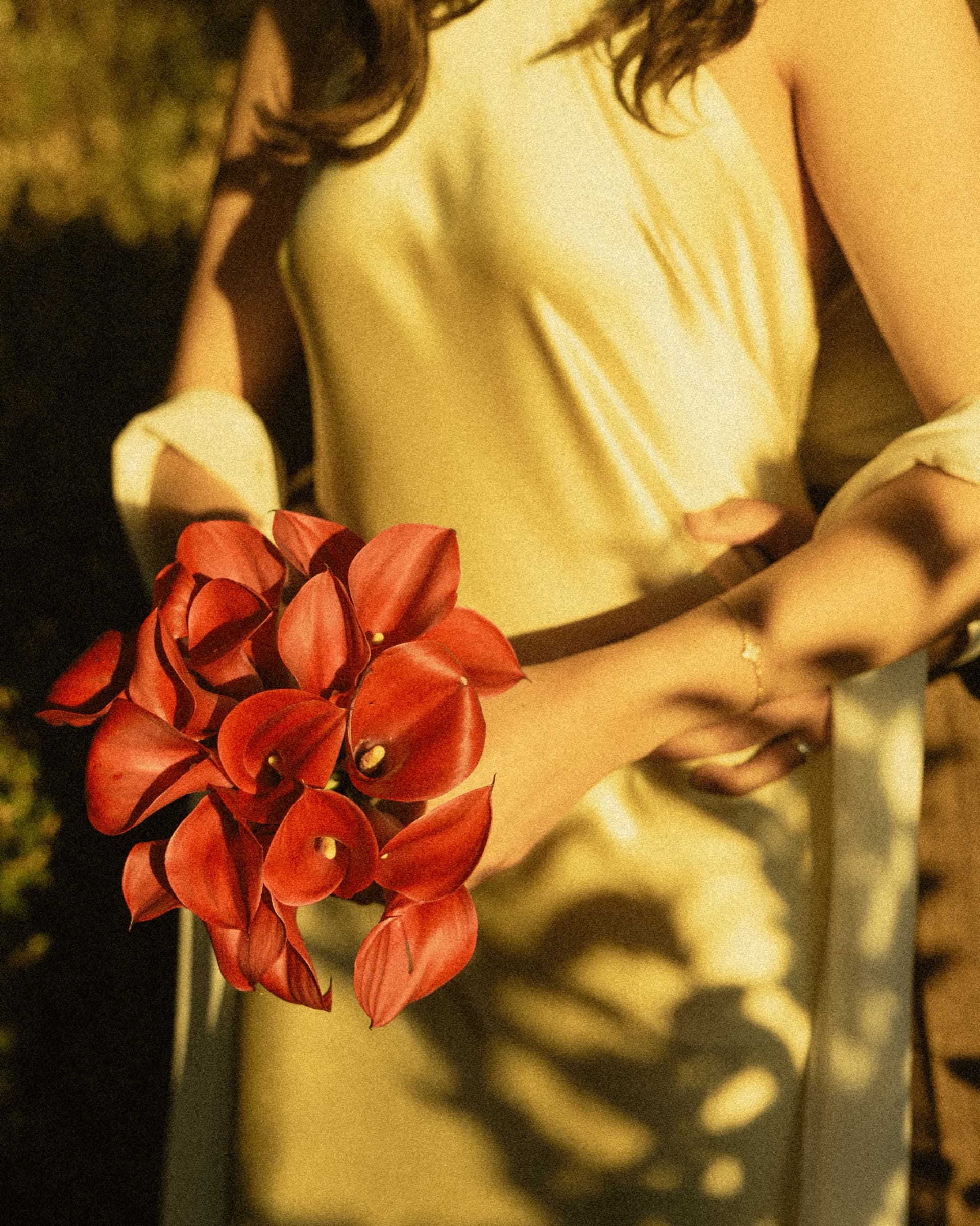 Detail of a deep red bouquet held against a silk dress